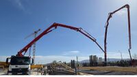 Large-scale concreting under a bright blue sky.