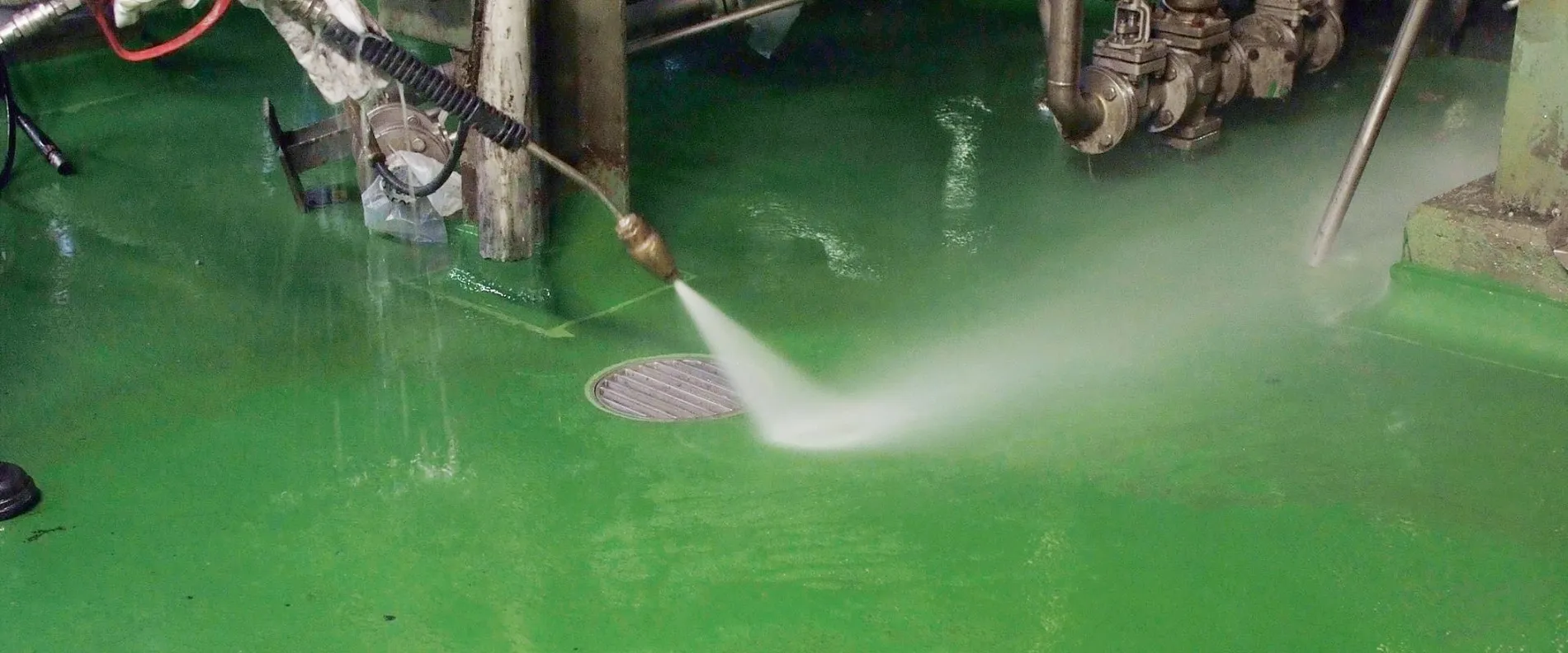 A green floor is cleaned by a water jet.