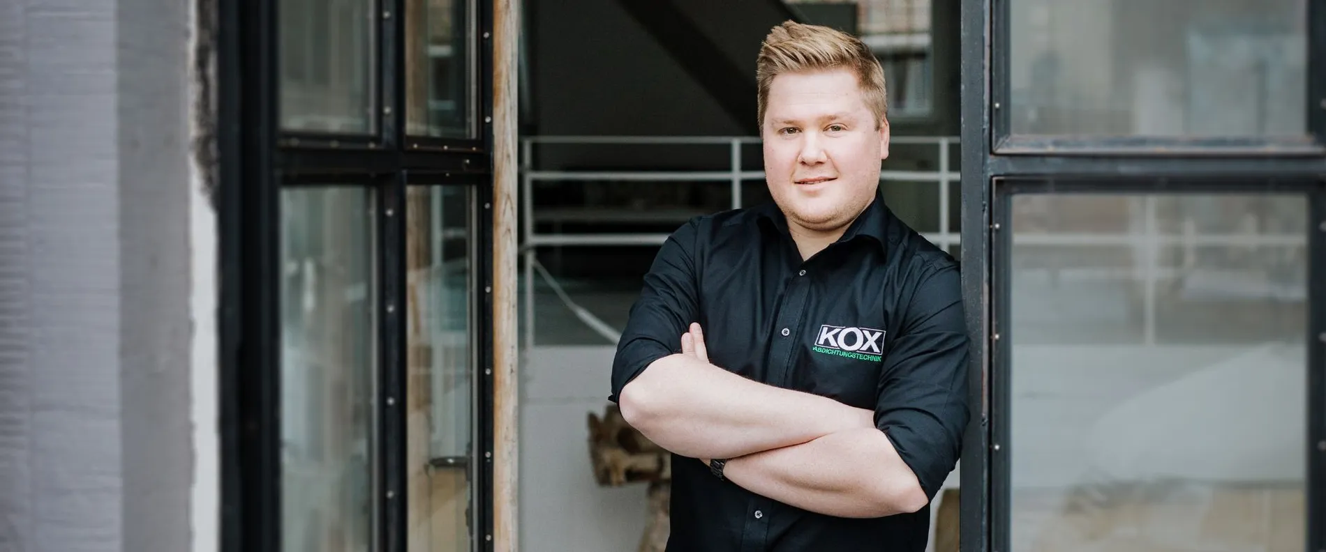 Dennis Kox standing in front of a building with crossed arms.